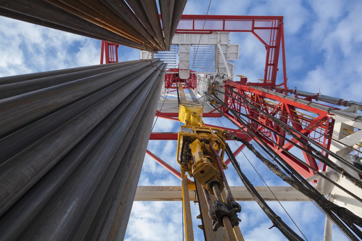 A stock photo of an oil drilling rig from the ground looking up